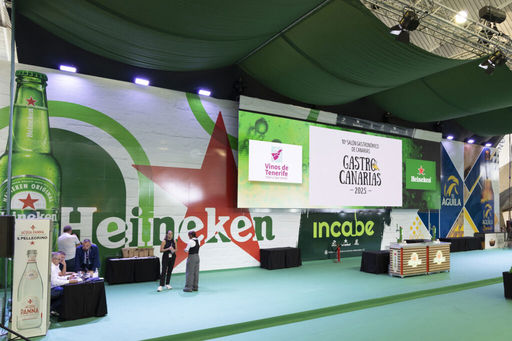 Exhibition hall with green Heineken branding, large bottle graphics, and a stage for Gastro Canarias 2025 at a gastronomy fair.